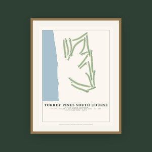 May include: A framed print featuring a map of the Torrey Pines South Course golf course. The design includes a light blue coastline, green fairways on a cream background, and text stating Torrey Pines South Course, La Jolla, California.