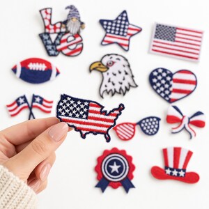 May include: A collection of embroidered patches featuring patriotic American themes, including a map of the USA, a bald eagle, a flag, a heart, a top hat, a football, sunglasses, a rosette, a bow, and the word LOVE with a gnome.