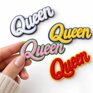 May include: Four embroidered patches featuring the word Queen in cursive script. One patch is white with a dark blue border, one is yellow with a blue border, one is pink with a green border, and one is red with a yellow border. The patches are fabric.