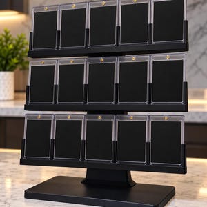 Op de afbeelding: Een zwarte displaystandaard met drie niveaus en vijftien doorzichtige magnetische kaarthouders van acryl, gerangschikt in drie rijen van vijf. Elke houder heeft een goudkleurige schroef aan de bovenkant en bevat een zwarte inzet.