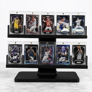 May include: A black two-tiered display stand holding ten sports trading cards in clear protective cases. The cards feature various athletes including LeBron James, Mike Trout, Patrick Mahomes, Connor McDavid, Shohei Ohtani, and Stephen Curry.