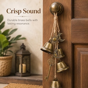 May include: A set of brass bells hanging from a door knob by jute twine. The decorative arrangement includes metal charms of a sun, a crescent moon, and an ornate skeleton key. Text on the image reads: Crisp Sound. Durable brass bells with lasting resonance.