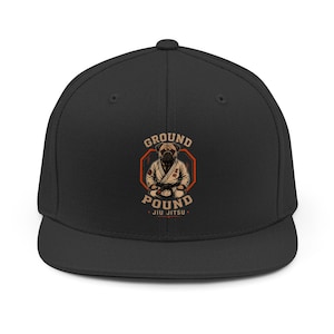 May include: A black snapback cap featuring a graphic of a pug wearing a white jiu-jitsu gi with a black belt. The design includes an orange octagonal border and the text "GROUND POUND JIU JITSU" in a bold, tan, sans-serif font centered on the front.