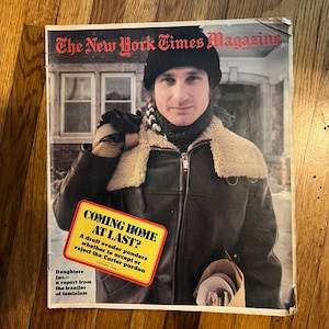 May include: The New York Times Magazine cover featuring a man in a brown leather jacket and a black knit hat. The headline reads "Coming Home At Last?" with the subheading "A draft evader ponders whether to accept or reject the Carter pardon."