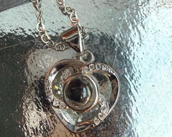 Glass stone surrounded by silver to make a heart, three spokes of rhinestones, pendant necklace with silver chain
