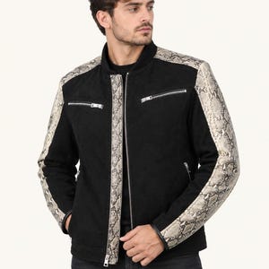 May include: A black jacket featuring a stand-up collar and long sleeves with a snakeskin pattern. The garment includes a central silver zip, two horizontal zipped chest pockets, and two side pockets, all accented with silver hardware.