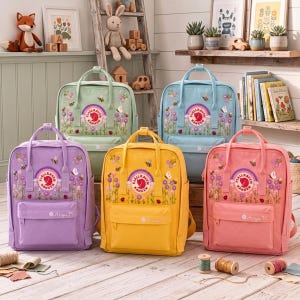 Könnte beinhalten: Fünf Fjallraven Kanken Rucksäcke in Hellgrün, Hellblau, Lila, Gelb und Pink. Jeder Rucksack hat ein kreisförmiges Logo, Tragegriffe, eine Vordertasche mit dem Text Anya M und gestickte Blumenmuster mit Bienen und Schmetterlingen.