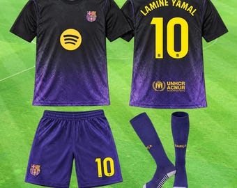 Könnte beinhalten: Ein schwarz-violettes Fußballtrikot-Set mit dem FC Barcelona-Wappen, einem gelben Spotify-Logo sowie dem Namen Lamine Yamal und der Nummer 10 auf der Rückseite. Das Set enthält passende violette Shorts mit der Nummer 10 und violette Fußballstutzen.