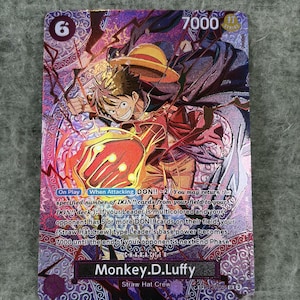 Op de afbeelding: Een paarse en rode One Piece ruilkaart met Monkey D. Luffy in een dynamische houding met een strooien hoed en een gloeiende rode vuist. De kaart toont de tekst Monkey D. Luffy, een krachtniveau van 7000 en gedetailleerde spelinstructies.