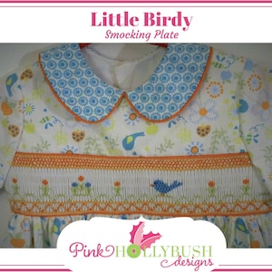 May include: A white baby dress with a blue floral collar and orange trim. The dress features a smocked bodice with a blue bird and floral design. The text "Little Birdy Smocking Plate" is at the top.
