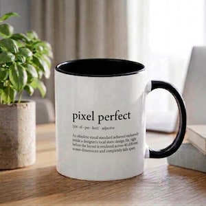 May include: A white ceramic mug with a black interior and handle. The front features the black text pixel perfect, followed by its phonetic spelling, the adjective label, and a humorous definition about design files and screen dimensions.