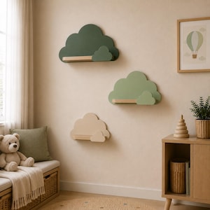 May include: Three wall-mounted floating shelves shaped like clouds, arranged vertically. The top shelf is dark green, the middle is sage green, and the bottom is beige. Each shelf features a small, secondary cloud accent and a light wood ledge.