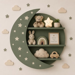 May include: A sage green crescent moon-shaped wall shelf with three horizontal tiers. The shelf features light-colored star cutouts and holds a teddy bear, a star-shaped lamp, a succulent, a rabbit plush, a rainbow, a framed sign reading dream big little one, a cloud plush, and a wooden car toy.
