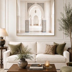 May include: A large square framed wall art print depicting a series of white arched doorways with intricate blue and white tile patterns on the pillars. The artwork is displayed above a white sofa with olive green and patterned throw pillows.