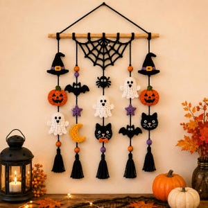 May include: A Halloween-themed wall hanging featuring crocheted figures including black witch hats, orange pumpkins, white ghosts, black bats, black cats, a spider, a crescent moon, and purple stars, all suspended from a wooden rod with black tassels.