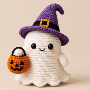 May include: A white crocheted ghost figurine wearing a purple witch hat with a black band and yellow buckle. The ghost has black bead eyes, a small stitched smile, and pink cheeks. It holds a small orange crocheted pumpkin bucket with a black handle.
