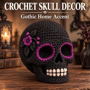 Puede incluir: Una calavera de ganchillo negra con detalles de hilo morado alrededor de las cuencas de los ojos, una pequeña flor morada con hojas oscuras en el lateral y dientes de hilo color crema. El texto CROCHET SKULL DECOR y Gothic Home Accent aparece.