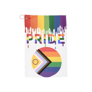 May include: A white rectangular towel featuring a rainbow-colored drip pattern at the top with the word PRIDE printed in block letters. Below the text is a circular Progress Pride flag design featuring horizontal stripes and a triangle.