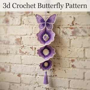 May include: A 3d crochet butterfly pattern hanging decoration featuring a purple and white gradient butterfly at the top, followed by three spiraling circular crochet elements with central star motifs, finished with a purple yarn tassel at the bottom.