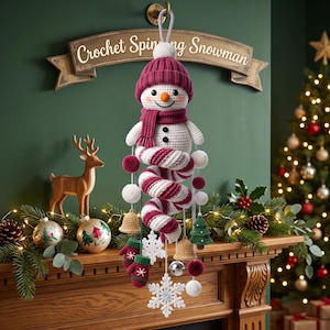 May include: A hanging crochet spinning snowman ornament featuring a white body, a dark red knit hat, and a matching scarf. The snowman has a spiral candy cane-style tail adorned with small crochet bells, mittens, white snowflakes, and pom-poms.