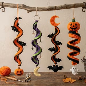 May include: Four hanging crochet spiral decorations featuring Halloween themes. The first is orange and black with bats and a jack-o'-lantern. The second is purple and green with stars. The third is black and orange with bats and a crescent moon. The fourth is orange and black with a jack-o'-lantern and a ghost.