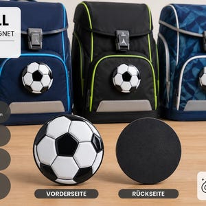 May include: Three school backpacks in navy, black, and patterned blue, each featuring a football magnet on the front. A separate football magnet is shown from the front and back, with text labels FUSSBALL SCHULRANZEN-MAGNET.