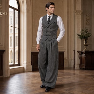 May include: A charcoal grey herringbone tweed double-breasted vest and matching wide-leg pleated trousers paired with a crisp white long-sleeved button-down shirt, a black necktie, and a black pocket square. The Vellurne logo is visible in the corner.