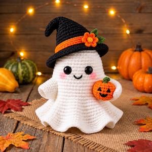 May include: A white crocheted ghost figurine wearing a black witch hat with an orange band and a small orange flower. The ghost has black bead eyes, pink cheeks, and a stitched smile, while holding a small orange crocheted jack-o'-lantern.