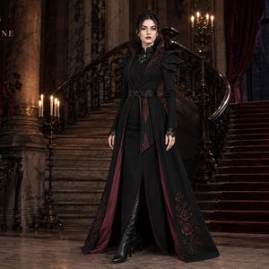 Victorian vampire coat for women in black and burgundy with embroidered floral details, dramatic shoulders and long gothic silhouette.