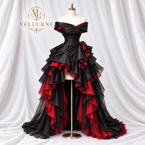 May include: A black and red off-the-shoulder gown featuring a high-low hemline with layered ruffled fabric. The bodice is fitted with a folded neckline, and the skirt displays a dramatic cascade of black and red tiers. The logo VELLURNE is visible.