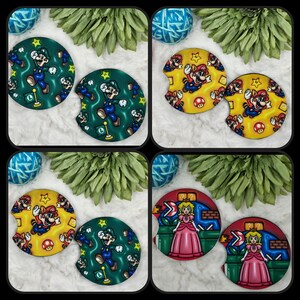 May include: Set of four round, printed car coasters. Two coasters feature a green background with a cartoon character in a green suit and a red cap. The other two coasters feature a yellow background with a cartoon character in a red suit and a red cap.