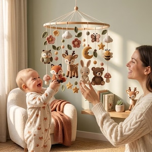 May include: A circular wooden baby mobile featuring various crocheted figures including a fox, deer, rabbit, bear, owl, bee, butterfly, moon, stars, flowers, and mushrooms, all suspended by white strings from a central wooden frame.