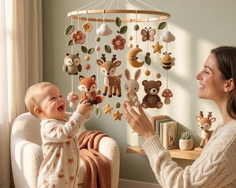 Puede incluir: Un móvil circular de madera para bebé que presenta varias figuras tejidas a ganchillo, incluyendo un zorro, un ciervo, un conejo, un oso, un búho, una abeja, una mariposa, una luna, estrellas, flores y setas, suspendidos por hilos blancos.