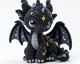 Puede incluir: Un peluche de dragón tejido a ganchillo en negro y gris con grandes ojos brillantes, cuernos pequeños y alas decoradas con patrones celestiales dorados bordados, incluyendo estrellas y una luna creciente en las alas.