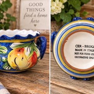 Peut inclure: Un bol en céramique avec deux anses, un bord festonné et des motifs de fruits peints à la main en jaune, orange et violet. Le dessous porte le texte : CER-BROGI MADE IN ITALY NOT FOR FOOD USE DECORATIVE ONLY. Le bol a une bordure bleue et jaune.