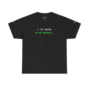 Może przedstawiać: Czarny t-shirt z krótkim rękawem z białym i zielonym napisem > it works on my machine._ nadrukowanym na klatce piersiowej. Koszulka posiada małe zielono-białe detale tekstowe na obu rękawach oraz metkę marki wewnątrz przy kołnierzu.