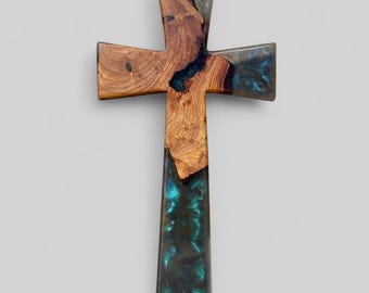 May include: A wooden cross with a teal and black resin inlay. The wood grain is visible on the cross.