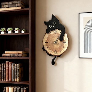 May include: A wall clock featuring a natural wood slice face with visible grain rings, black hour markers, and thin hands. A black cat silhouette with large white eyes is attached to the top and bottom, appearing to hug the circular wood clock face.