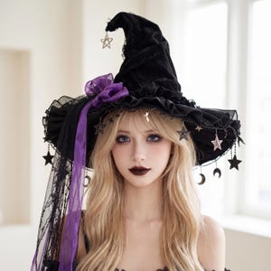 May include: A black velvet witch hat featuring a wide ruffled brim, a purple organza bow, and a long black lace veil. The hat is adorned with dangling metal charms in the shapes of stars and crescent moons hanging from the brim edge.