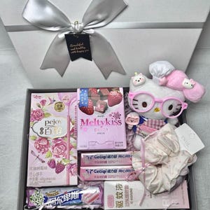 May include: A gift box containing a Hello Kitty plush wearing pink glasses, a box of Pejoy rose-flavoured biscuit sticks, a box of Meiji Meltykiss strawberry chocolates, two Geliqi snack bars, a polka dot scrunchie, and a mosquito repellent bottle.