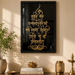 Peut inclure: Un cadre rectangulaire noir contenant un fond noir avec un texte en sanskrit de couleur dorée écrit dans une disposition verticale stylisée. Le texte présente le symbole Om en haut et des fioritures décoratives au bas de l'écriture.