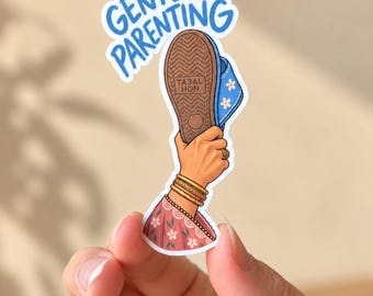 May include: A sticker featuring a hand holding a blue slipper with a brown sole and white flower patterns. The text GENTLE PARENTING is written in blue above the slipper. The hand wears gold bangles and a ring, and the sleeve is pink with white flowers.