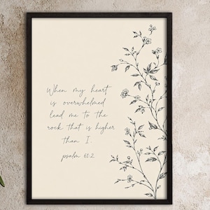 May include: A rectangular wall art print in a black frame featuring a cream background with black line art of a flowering vine on the right and the text: When my heart is overwhelmed lead me to the rock that is higher than I. Psalm 61:2.