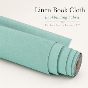 Puede incluir: Un rollo de tela de lino para encuadernación en color verde azulado claro con una textura tejida visible. El texto en la imagen dice: Linen Book Cloth, Bookbinding Fabric, For Book Covers • Journals • DIY. La tela está enrollada en un núcleo de cartón.