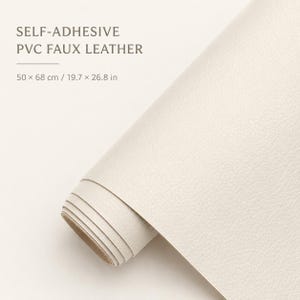 Puede incluir: Un rollo de piel sintética de PVC autoadhesiva en color blanco roto con una superficie texturizada. El texto en la imagen dice: SELF-ADHESIVE PVC FAUX LEATHER, 50 x 68 cm / 19.7 x 26.8 in. El material se muestra parcialmente desenrollado.