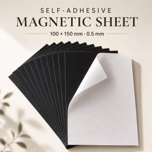 Könnte beinhalten: Ein Stapel rechteckiger, selbstklebender Magnetfolien mit einer schwarzen magnetischen Seite und einer weißen abziehbaren Rückseite. Der Text auf dem Bild lautet SELF-ADHESIVE MAGNETIC SHEET 100 x 150 mm 0.5 mm. Die Folien sind schwarz und weiß.
