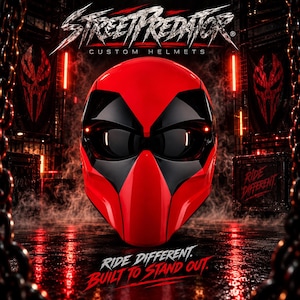 May include: A glossy red and black motorcycle helmet featuring a stylised face design with dark eye visors. The text STREETPREDATOR CUSTOM HELMETS appears at the top, while the text RIDE DIFFERENT BUILT TO STAND OUT is printed at the bottom.