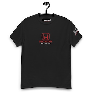 May include: A black short-sleeve t-shirt featuring a red Honda logo and the text HONDA MOTOR CO. centered on the chest. The inner neck label displays the text THROTTLE, and the left sleeve features the script text Small Big Dreams.