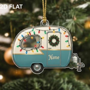 May include: A flat, two-dimensional camper ornament featuring a cream and teal exterior, decorated with a string of colorful Christmas lights, a green wreath on the door, and the word Name printed in gold script, suspended by a gold cord.
