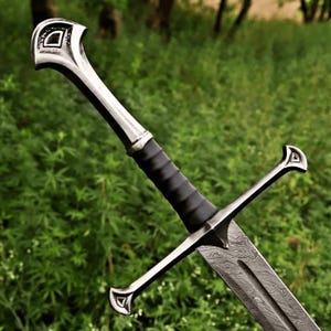 May include: A sword featuring a patterned Damascus steel blade with a central fuller. The hilt includes a black leather-wrapped grip, a polished silver-coloured crossguard, and a matching pommel, both decorated with a small triangular cutout detail.